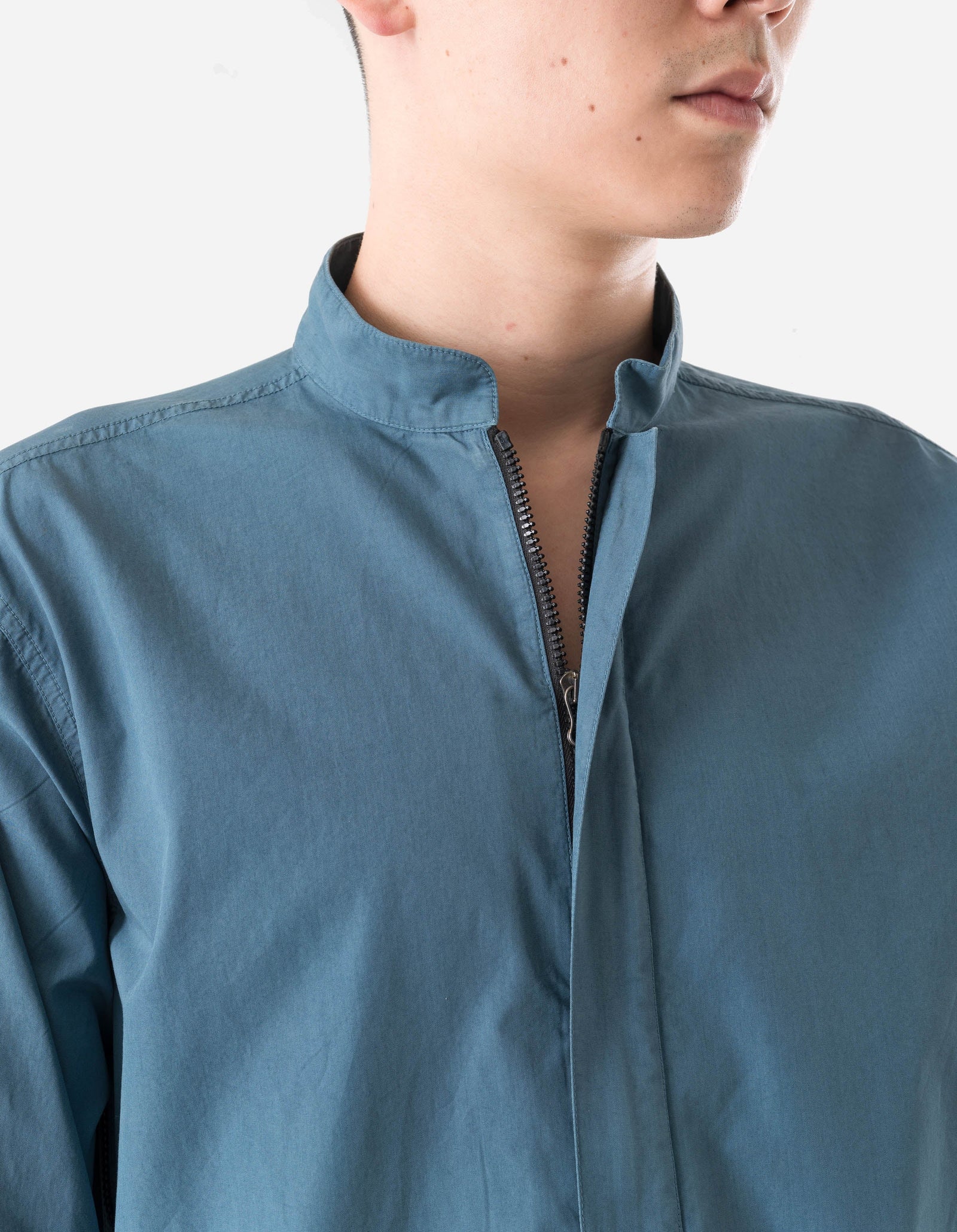Close-up of a person wearing a blue jacket with a zipper on a white background